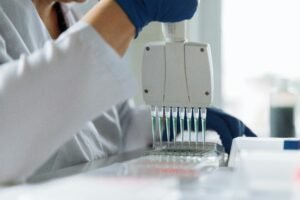 Universitário pipetando amostra de material biológico no laboratório de pesquisa